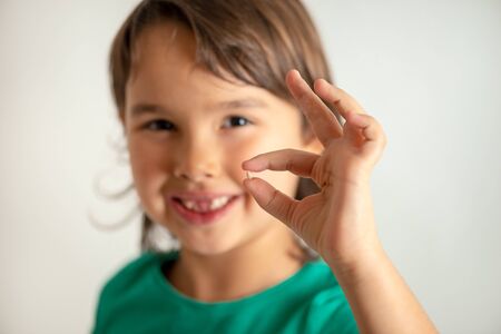 Girl with tooth in hands on isolated white background. Happy and proudの写真素材