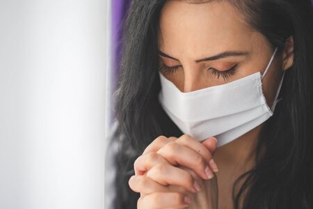 Portrait of woman with surgical mask prayingの写真素材