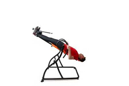 Man doing exercise on inversion table for his back pain, isolated on whiteの写真素材