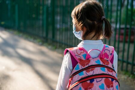 Little school girl going back to school after pandemic outbreak wearing an face maskの写真素材
