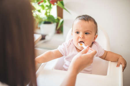 Mother feed her little daughter with a spoon