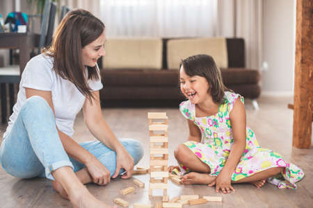 Young mother with her little daughter play game in wood blockの写真素材