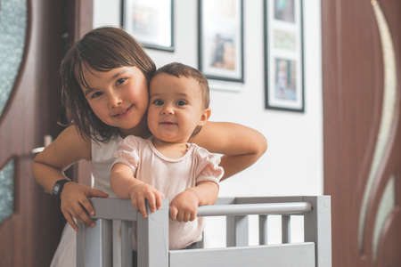 Girl play with her little sister at home. They have fun when walk on all foursの写真素材