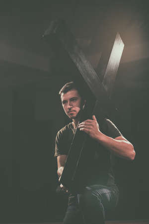Young man carrying a wooden cross.の写真素材