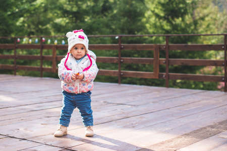 Small adorable infant standing on all fours on wooden floor at home.の写真素材