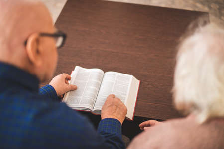 Elderly couple reading bible and pray together at home.の写真素材