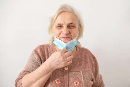 Depressed mature woman isolated on grey studio background touch cheek suffering from tooth pain, unhappy senior woman feel unhealthy unwell having painful toothache feeling, need dental treatmentの写真素材