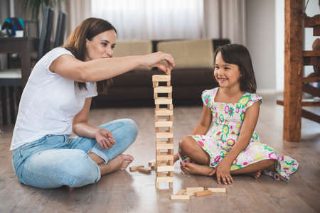 Young mother with her little daughter play game in wood blockの写真素材