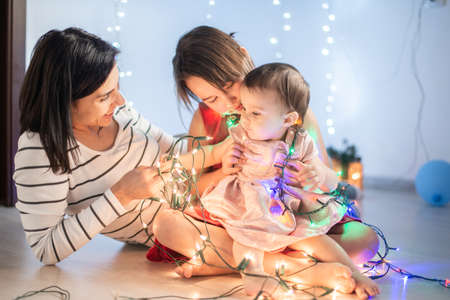 Mother with her daughters play with christmass lightsの写真素材