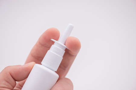 Holding nasal spray between fingers isolated on white backgroundの写真素材