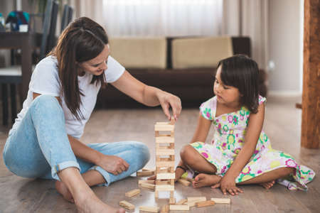 Young mother with her little daughter play game in wood blockの写真素材