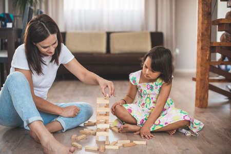 Young mother with her little daughter play game in wood blockの写真素材