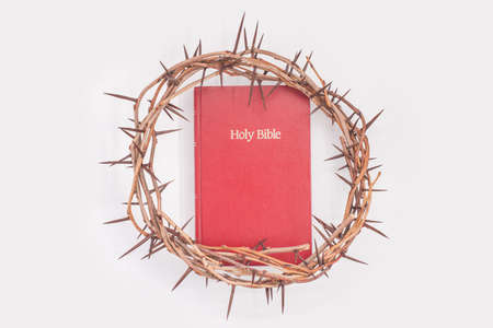Crown of thorns and red bible isolated on white
