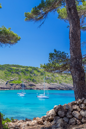 Beautiful Menorca island cove with yachts floating on turquoise water, Balearic islands, Spainの写真素材