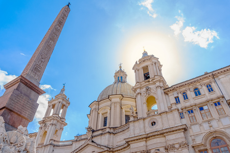 Sant'Agnese in Agone church and obelisk of Fontana dei Fiumi fountain on the Piazza Navona with bright sun shining from the bell tower, Rome, Italy.の写真素材