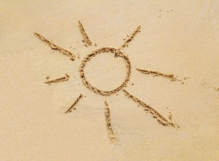 Beach sand surface with simple sun drawn on it. Summer background.の写真素材