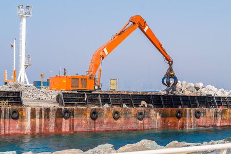Sea Shore Reinforcement Works with Excavator Standing on Floating Platform.の写真素材