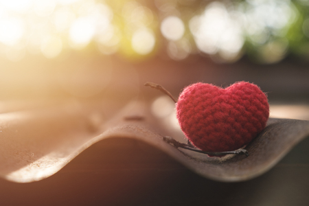 Red heart knitting on roof in mornig sun.の写真素材