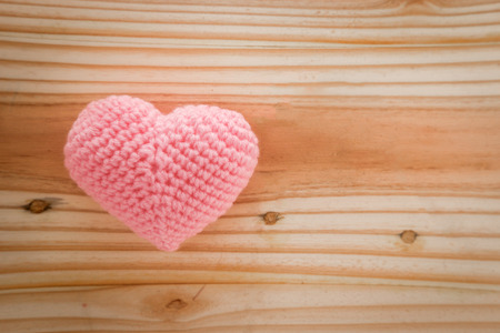 Pink heart knit with yarn on wooden floor.の写真素材