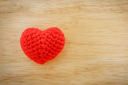Red heart knit with yarn on wooden floor.の写真素材