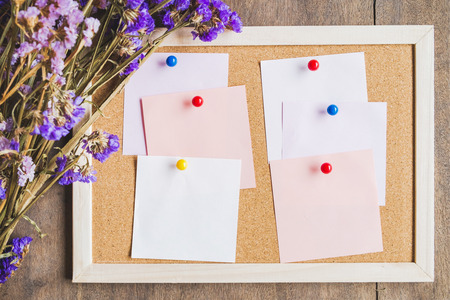 Blank notes on the cork board with dry flower bouquet,wooden background.