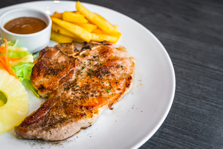 kurobuta pork chop with vegetable and french fries in white dish.の写真素材