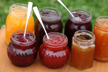 Glass with strawberry, cherry, orange, plum, blackcurrant and peach jam and spoons