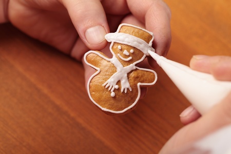 Close up of hands decorating Christmas cookie