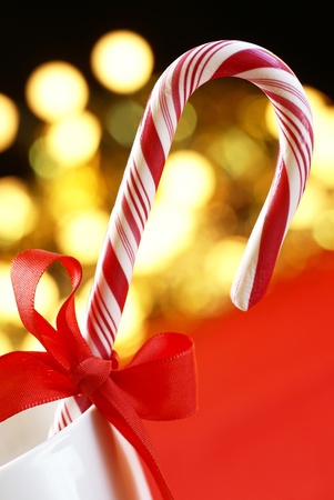 Candy cane with red ribbon on holiday lights backgroundの写真素材