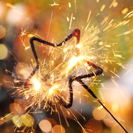 Close-up of holiday sparkler and defocused lights on background.の写真素材