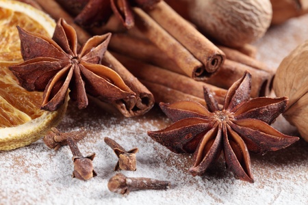 Cinnamon sticks, anise stars, nutmegs, cloves, nuts and vanilla beans on sugar background.