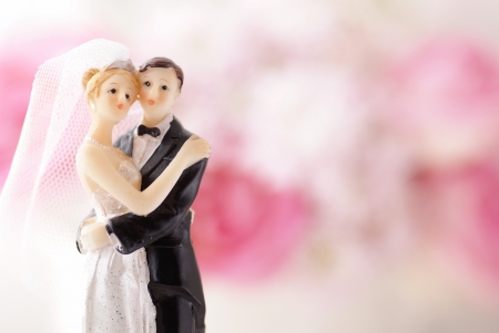 Figurines of wedding cake topper with flowers in backgroundの写真素材