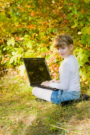 Little girl with a laptop in the parkの写真素材