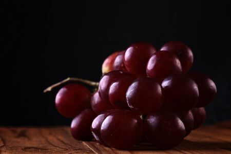 Red grape on wooden table on black backgroundの写真素材