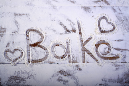 Wooden table top with love bake word text on flour background, horizontal pictureの写真素材