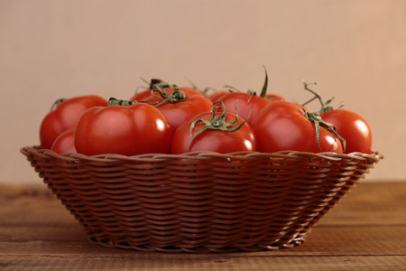 Ripe tomatoes in basket on wooden tableの写真素材