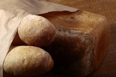 Loafs of white and rye bread in paper packet closeup, horizontal picture
