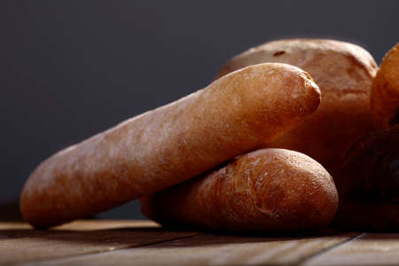 Fresh french bread laying on table on grey background closeup, horizontal picture