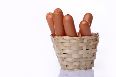 Appetizing sausages in a light brown wicker basket standing on white background copy space, horizontal photoの写真素材