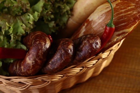 Meat home made sausages lattuce bread rolls and red pepper in basket closeup, horizontal pictureの写真素材