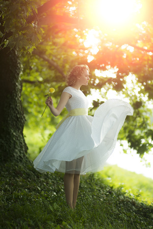 Beautiful young woman standing near tree in a summer parkの写真素材
