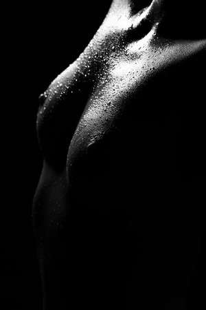 Beautiful and sensual naked woman breast close up on black background in black and whiteの写真素材