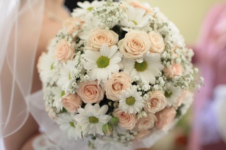 Closeup of beautiful wedding bunch of rose and chrysanthemumflowers pink orange, white colours with bride on blur background, horizontal pictureの写真素材