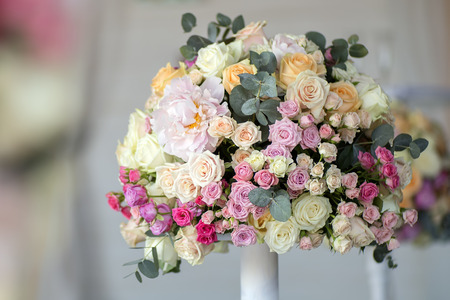Decoration of wedding posy of fresh beautiful flowers of roses and peony white pink violet purple yellow lilac and orange colours in slim vase indoor, horizontal pictureの写真素材