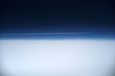 Abstract beautiful view of sky line with plane leaving trail in sky divided into two parts dark blue and white colours on air height space natural background, horizontal pictureの写真素材