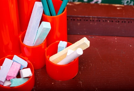 Colorful pencils of red yellow orange violet purple pink green and blue in stationary cup ruler and chalk on brown desk school background copyspace, horizontal pictureの写真素材