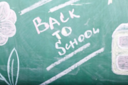 Blur texture background of green written with white and pink chalk blackboard with back to school text flower and bag with lines, horizontal pictureの写真素材