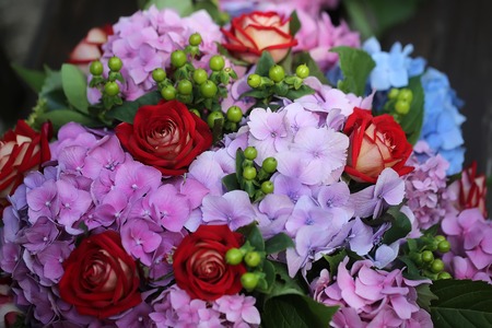 Closeup of beautiful fresh colorful summer bunch of cut flowers with red roses voilet and blue hydrangea and green buds, horizontal pictureの写真素材