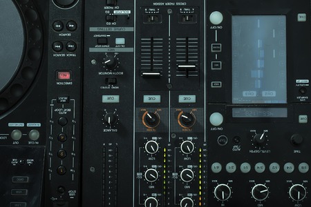 Upper view closeup of dj musical mixer electronic professional console black color with many buttons...