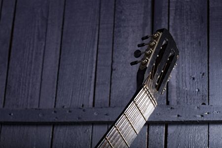 Closeup of fretboard of one acoustic string wooden musical instrument of guitar indoor in studio on gery wooden backdrop copyspace, horizontal pictureの写真素材